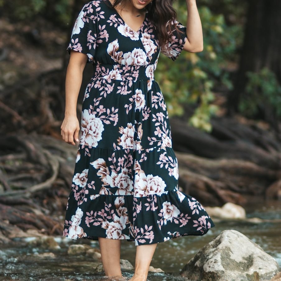 woman in black white and red floral dress standing on brown soil